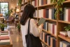 Une lectrice parcourt une étagère de livres reliés génériques sans couvertures ni titres.